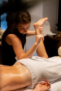 A therapist giving a sports massage with a leg stretch at Saya Club