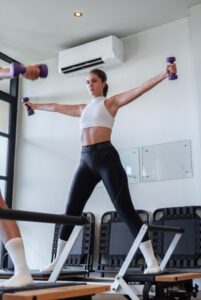 A member using hand weights in the SAYA Pilates reformer studio